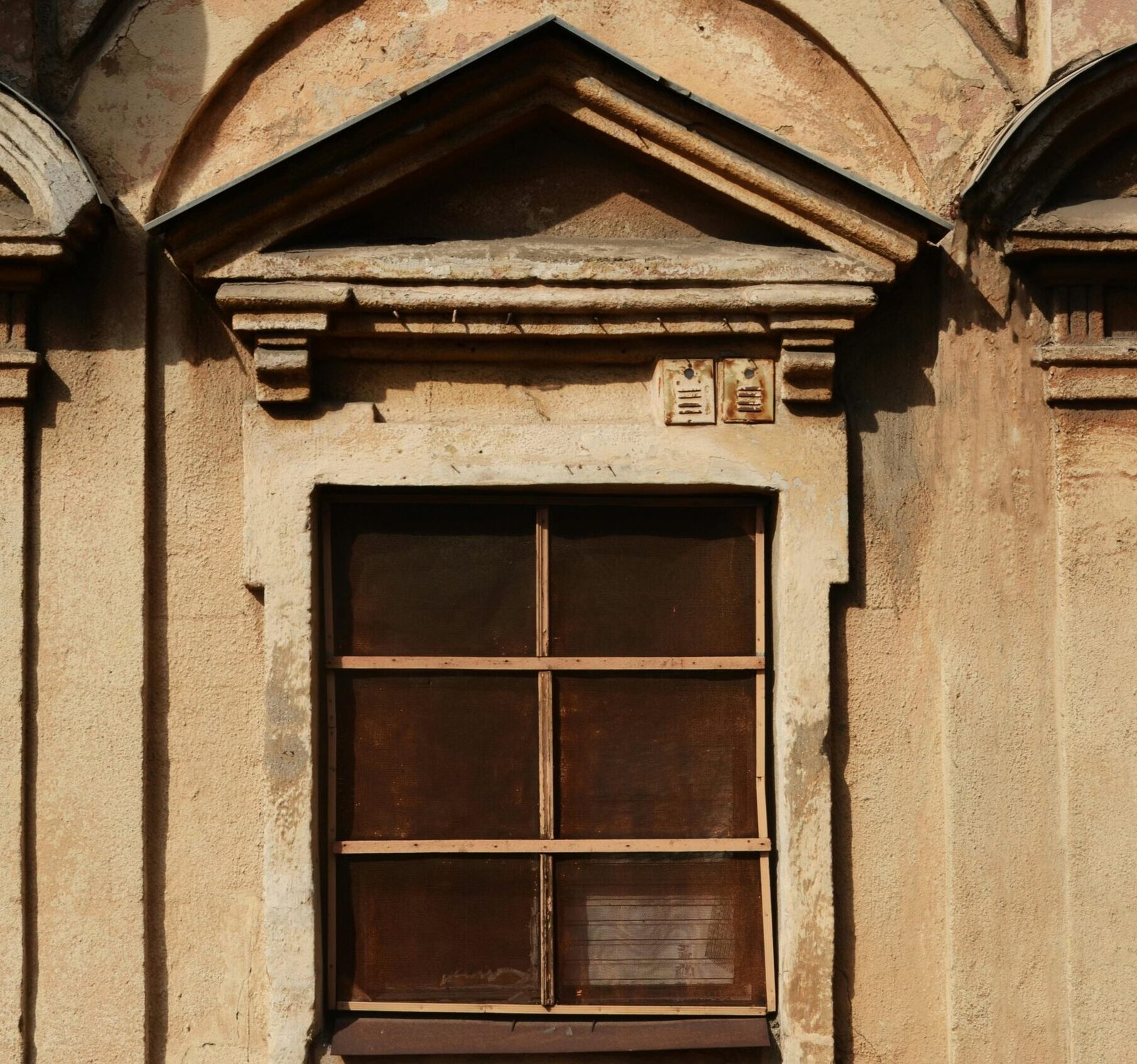 A vintage window on a rustic building exterior showcasing classic architectural details.